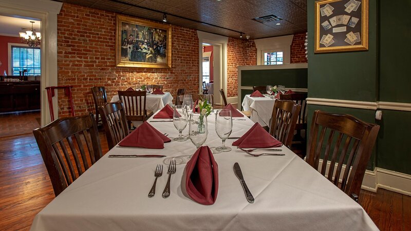 Dining room table set for four with red napkins and white table cloth