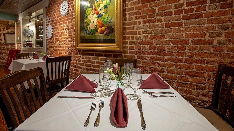 Dining room table set for four with panting of flowers on brick wall