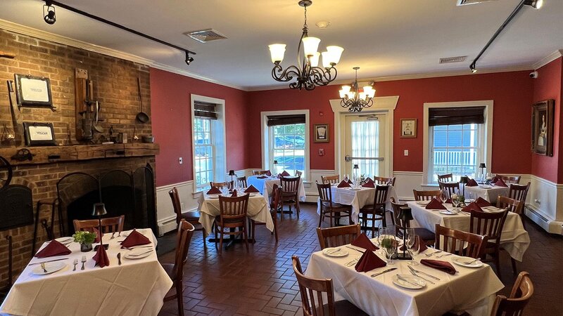 Dining room with red walls, set tables and fireplace