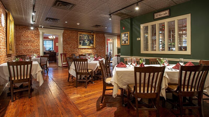 Dining room with green and brick walls with set tables